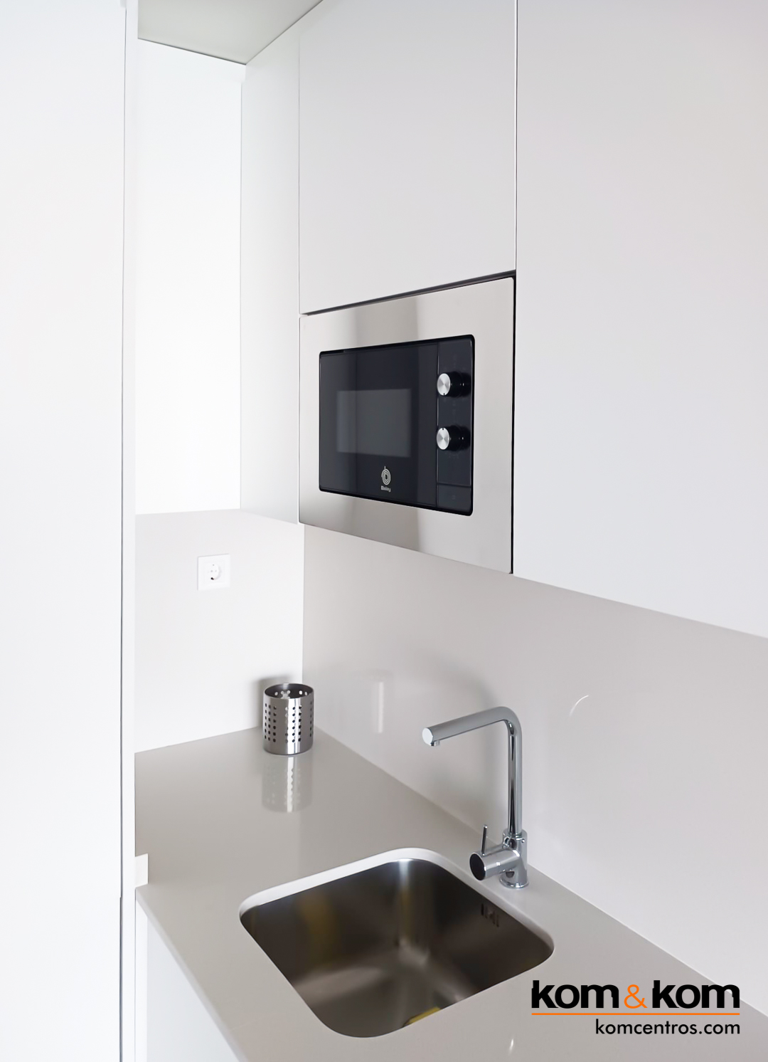 Cocina blanca con muebles altos cerrados al techo.